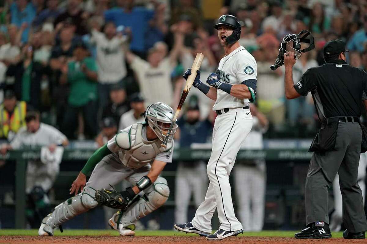 Seattle Mariners' Mitch Haniger yells as Oakland Athletics catcher Aramis Garcia moves to chase down a wild pitch in the ninth inning of a baseball game Saturday, July 24, 2021, in Seattle. Mariners' Jarred Kelenic scored from third and the Mariners won 5-4. (AP Photo/Ted S. Warren)