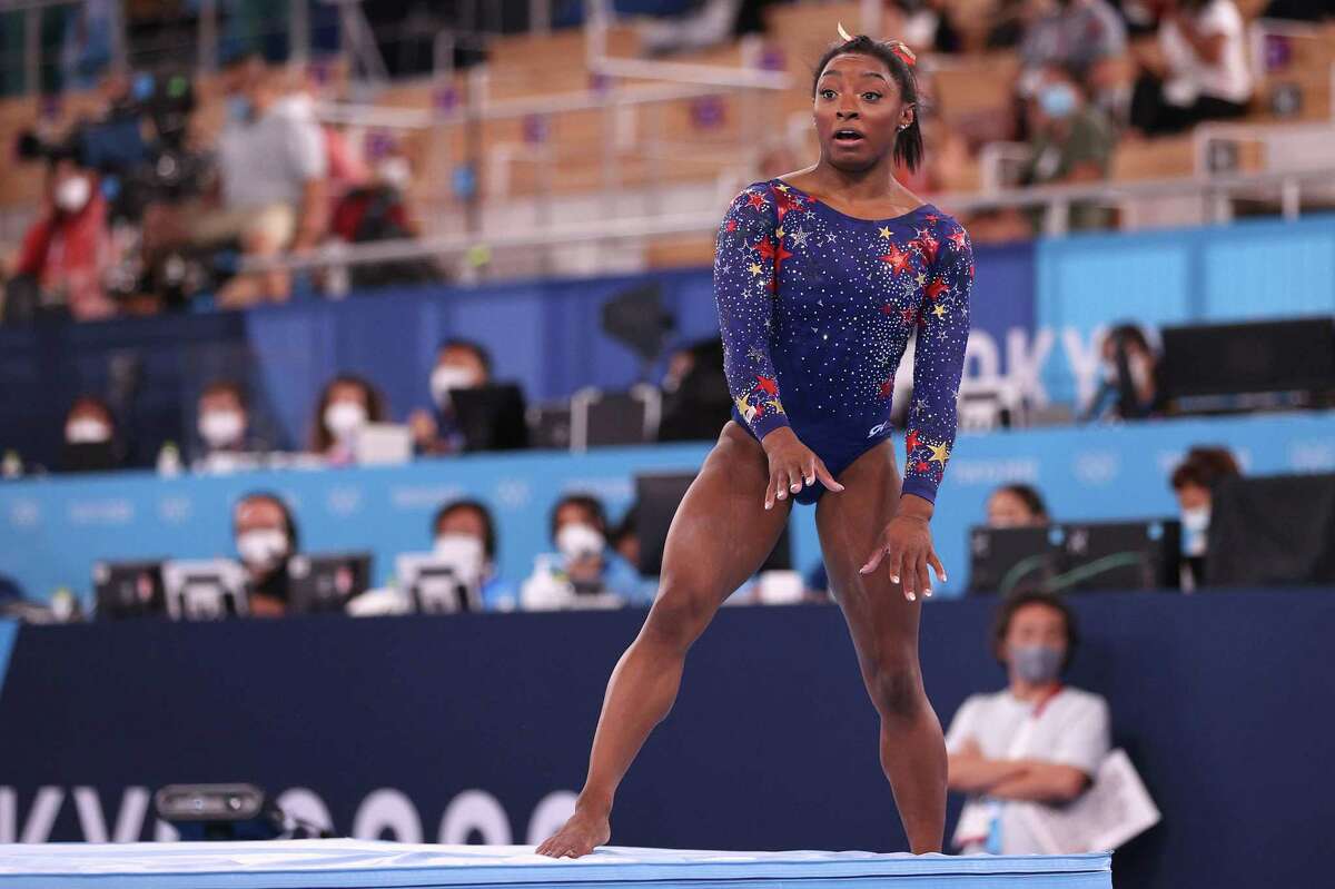 Simone Biles reacts after falling off the mat on her dismount from balance beam during women's gymnastics qualifications.