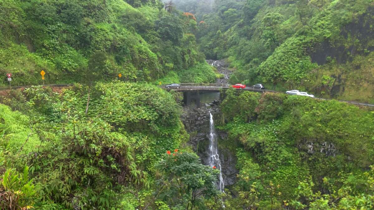 Traffic slows at a narrow bridge above a waterfall on Maui's famous road to Hana. 
