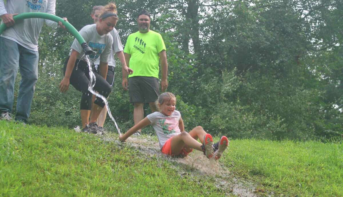 Runners slide down a muddy hill during West Shore Community College's Muddy Fox Trot 5K on the campus Saturday. The family friendly run raises money for the WSCC Foundation student scholarship fund. (Kyle Kotecki/News Advocate)
