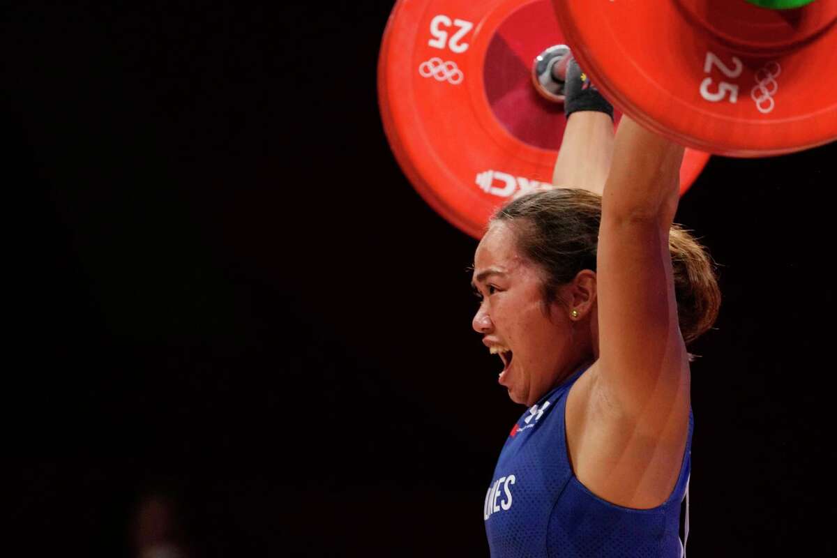 Hidilyn Diaz of Philippines celebrates as she competes and sets new world record and won the gold medal in the women's 55kg weightlifting event, at the 2020 Summer Olympics, Monday, July 26, 2021, in Tokyo, Japan.