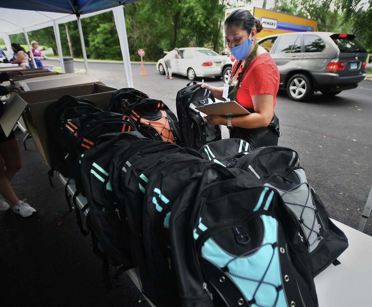 Volunteer Alicia Ochoa chooses a backpack to fill to a child's specifications during the annual back-to-school shop drive-thru distribution at Davenport Ridge Elementary School in Stamford, Connecticut on Sunday, July 25 2021.