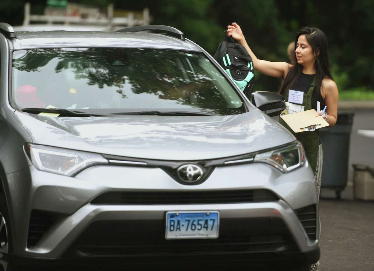 Volunteer Lorena Fernandez delivers a backpack to a waiting car during the annual Back to School Store Distribution at Davenport Ridge Elementary School in Stamford, Conn. on Sunday, July 25, 2021.