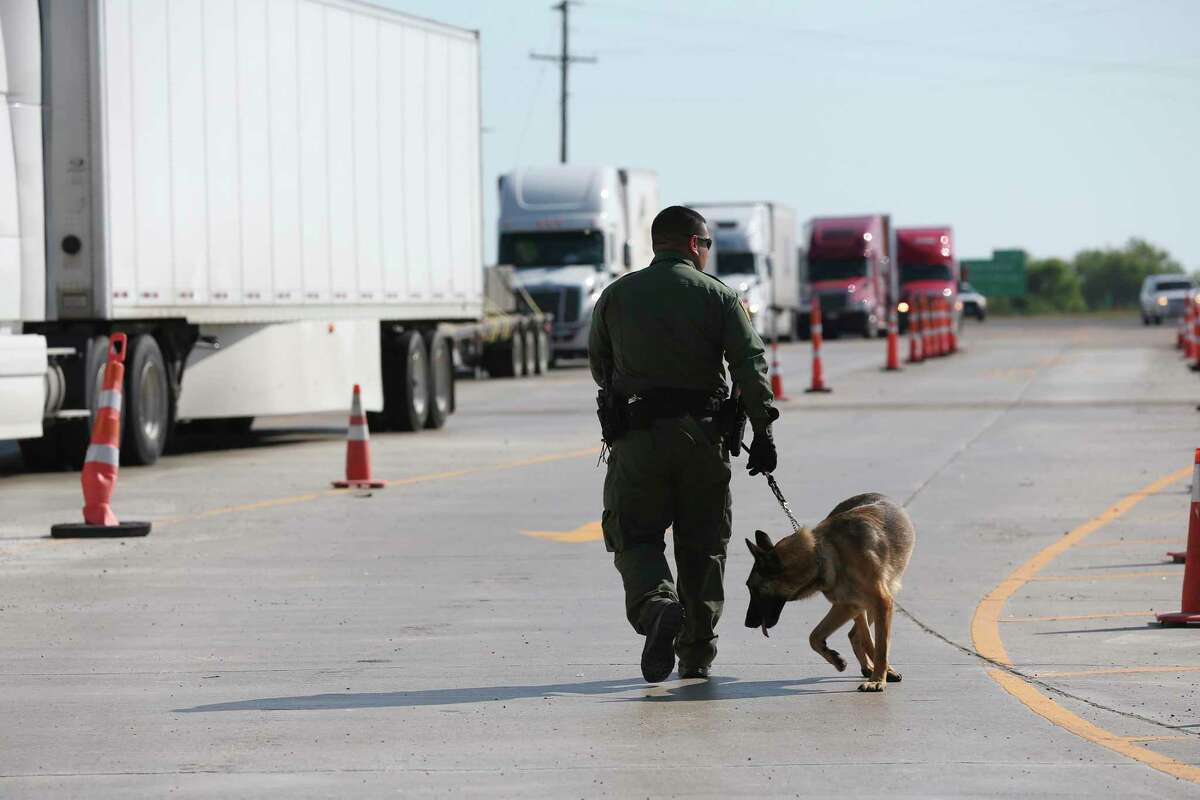 A U.S. Border Patrol K-9 unit works the tractor trailer lane at the Laredo checkpoint near Encinal, Texas in 2018. A Montgomery County man and woman were charged Thursday in federal court for allegedly trying to smuggle 89 people in a tractor trailer north of the U.S.-Mexico border.