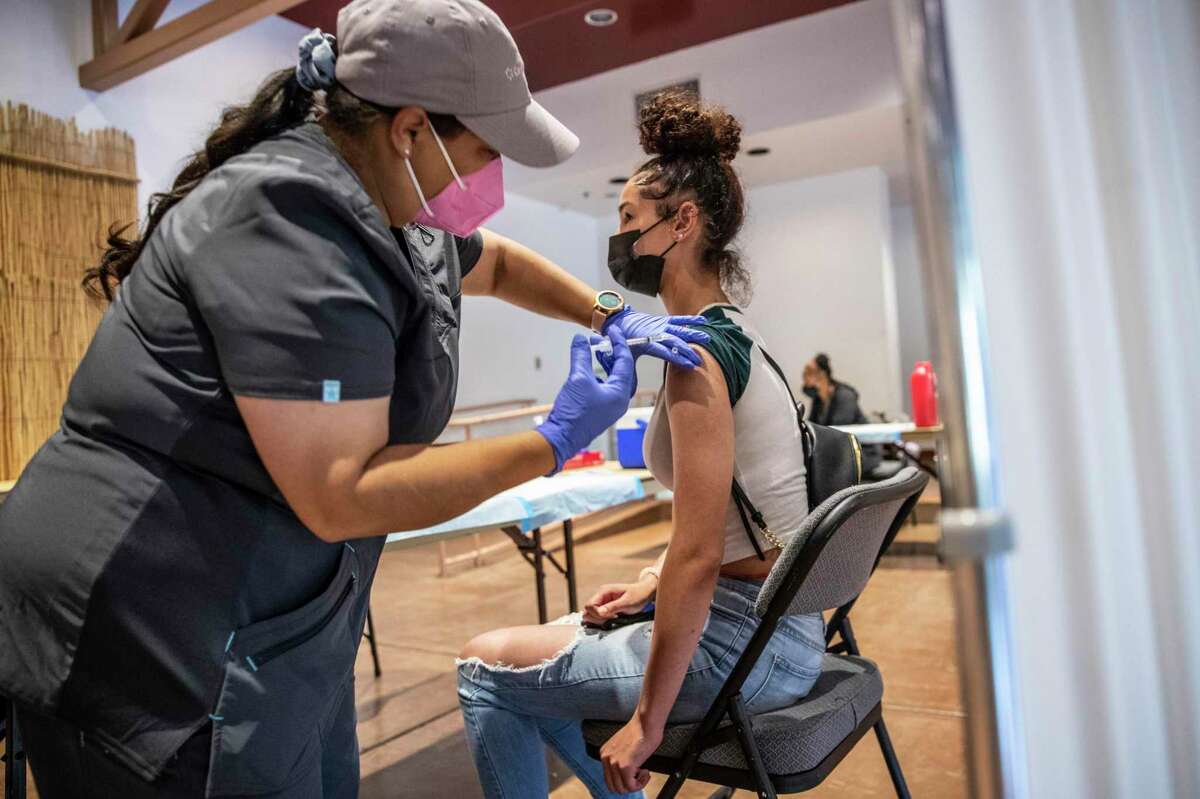 Maxine Grant, right, receives a first dose of the COVID-19 vaccine from medical assistant Patricia Ruiz during a pop-up clinic at Oakland Zoo.