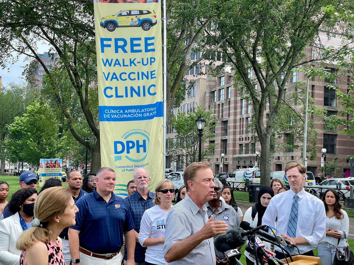 Gov. Ned Lamont's message to the young and unvaccinated: "It's about the team. It's not just about you." At right is Mayor Justin Elicker. Behind the governor in the blue shirt is Glen Lungarini, the executive director of the Connecticut Interscholastic Athletic Conference.