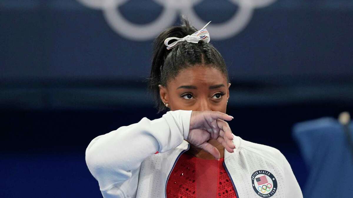Simone Biles, of the United States, watches gymnasts perform after she exited the team final with apparent injury, at the 2020 Summer Olympics, Tuesday, July 27, 2021, in Tokyo. The 24-year-old reigning Olympic gymnastics champion Biles huddled with a trainer after landing her vault. She then exited the competition floor with the team doctor. (AP Photo/Ashley Landis)