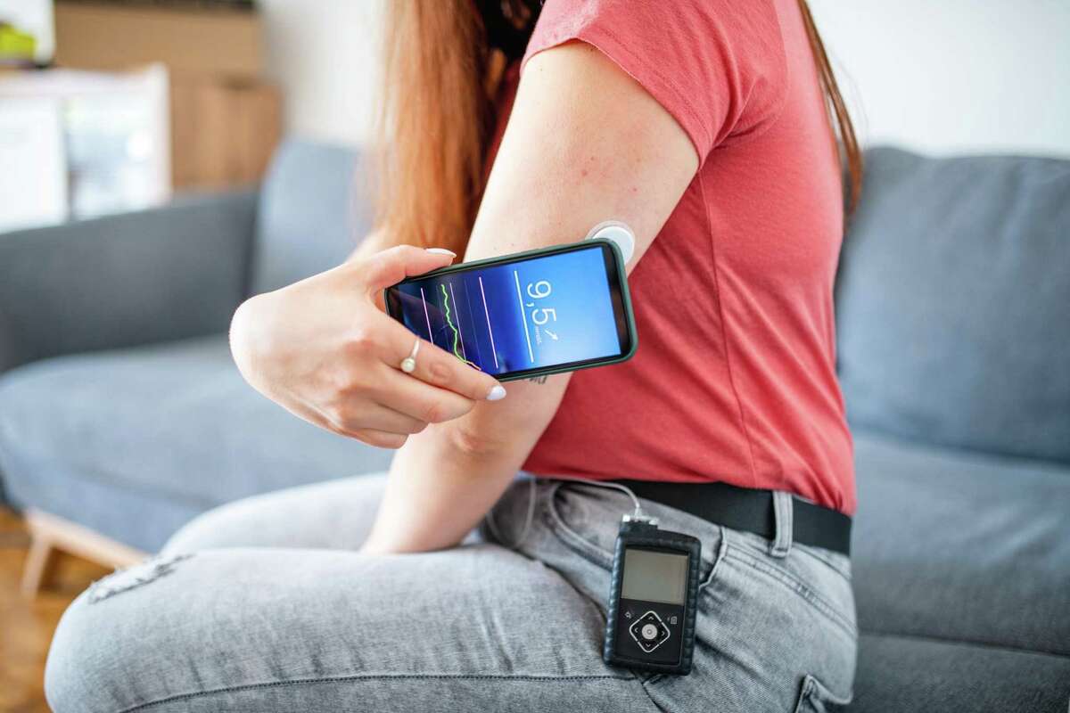 A woman swipes a sensor to determine glucose measurement.