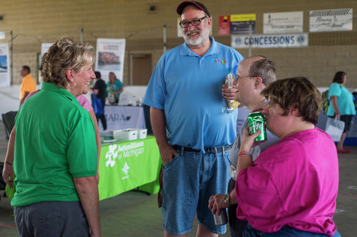 Kathy Allen, executive director of Personal Assistance Options, left, chats with guests during a community picnic hosted by PAO in partnership with Disability Network of Mid-Michigan celebrating the 31st anniversary of the Americans with Disabilities Act Monday, July 26, 2021 at Auburn City Park. The event featured food trucks, live music, bounce houses, kayaking, fishing and resource tables. (Katy Kildee/kkildee@mdn.net)