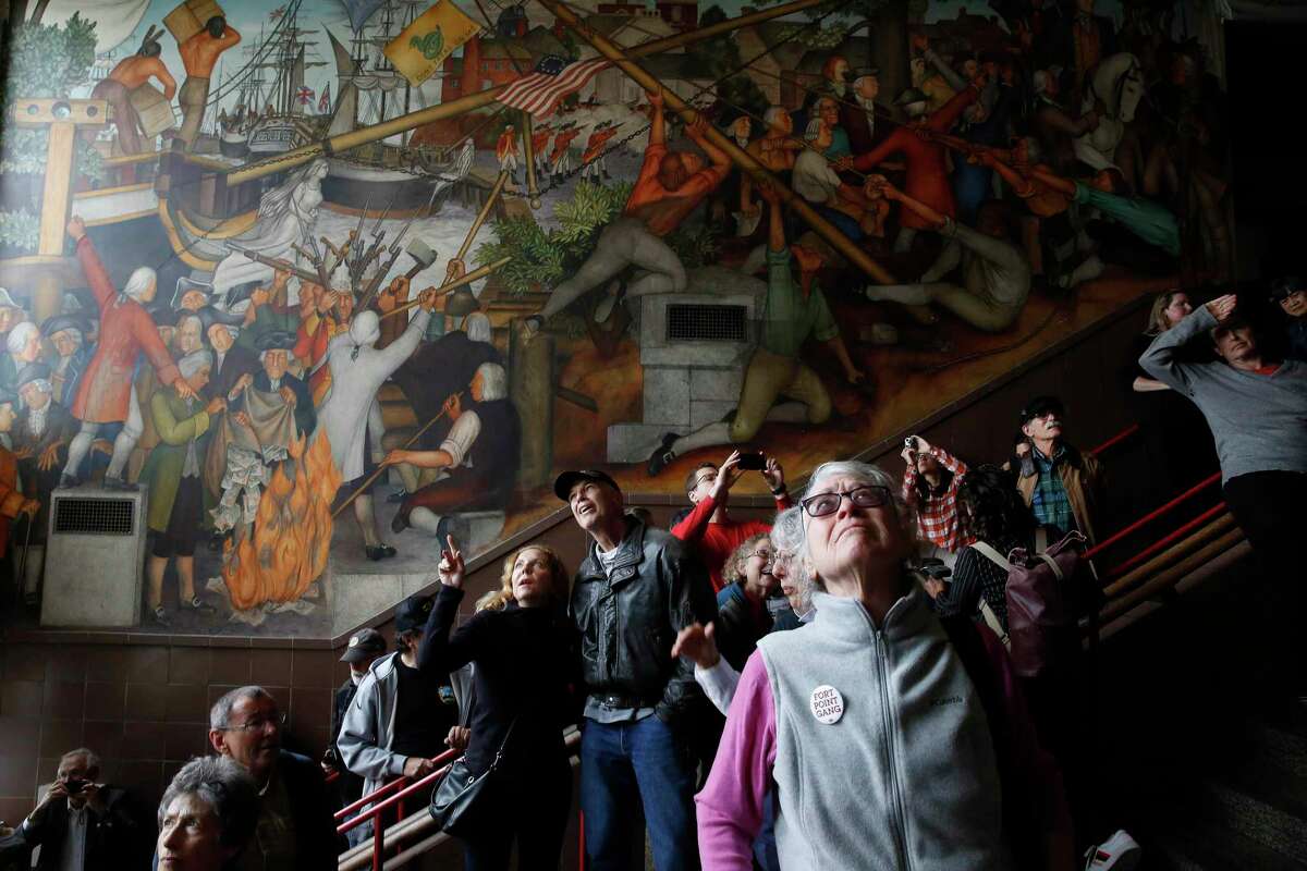 FILE —Vanya Akraboff (l to r) of Sausalito and Jeff Nemy discus the 1936 mural depicting the life of George Washington by San Francisco artist Victor Arnautoff at George Washington High School as Jean Amos of San Francisco views it during a public viewing on Thursday, August 1, 2019 in San Francisco, Calif.