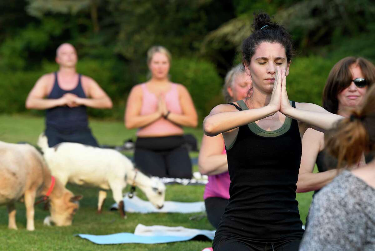 Ridgefield resident Alyse Dollard, right, participates in a session of goat yoga on Monday, July 26, 2021 in Ridgefield, Conn.
