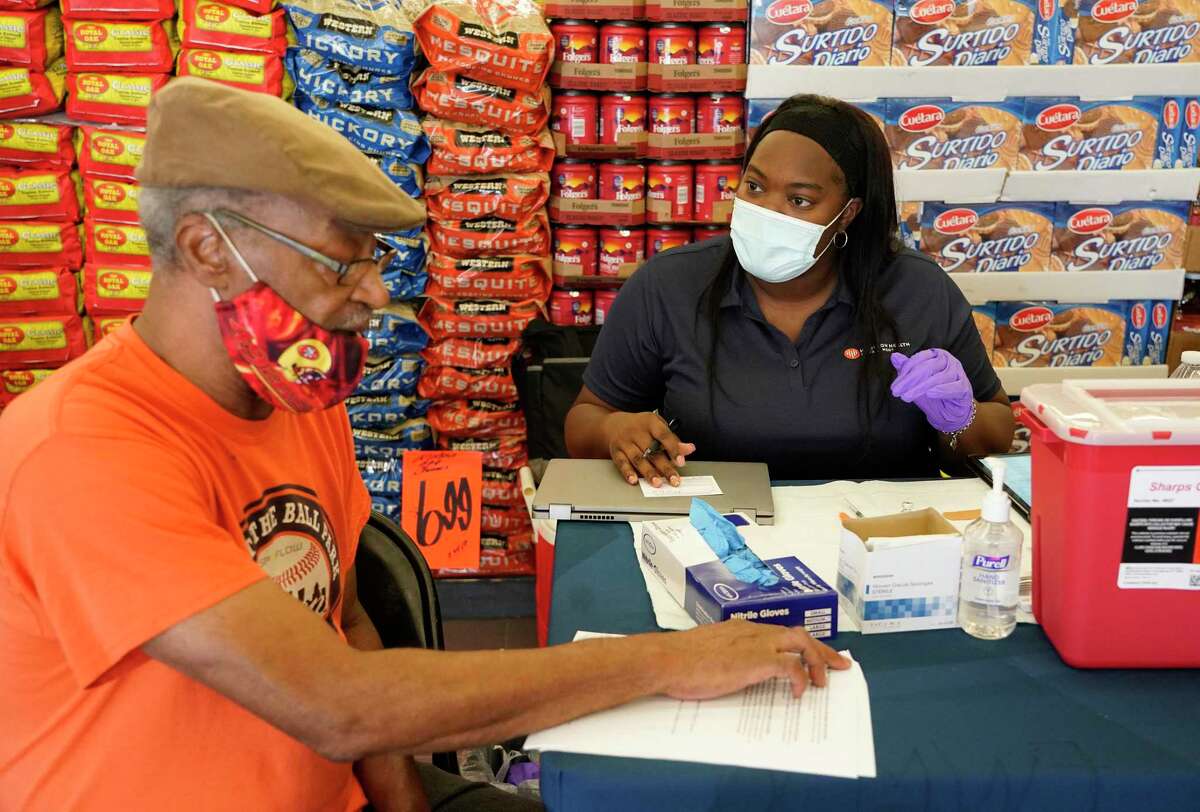 David Brown, left, talks to Kiosha Martin, LVN, right, with Houston Health Department, about getting a vaccination during an event held at Food Town, 5367 Antoine Dr., Tuesday, July 27, 2021 in Houston. After seeing the possible side effects, he decided not to take the vaccination.