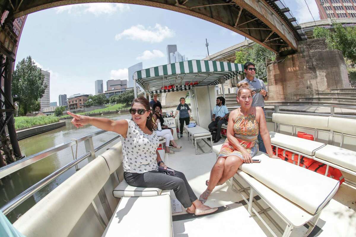 Amy Vargas (left) points toward a mural with her co-workers Rebecca Leija and Juan Sorto during a Buffalo Bayou Partnership boat tour Tuesday, July 20, 2021, in Houston. The Buffalo Bayou Partnership recently reopened boat tours to the public.