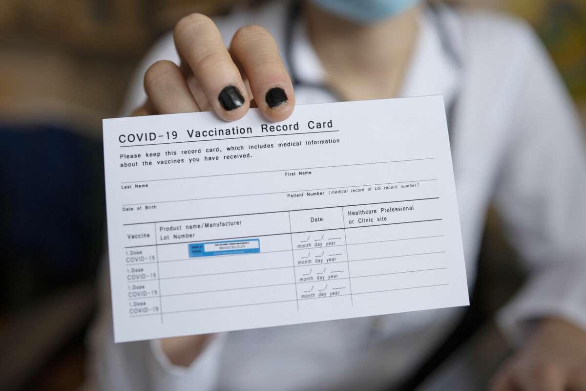 Close up of person holding a COVID-19 vaccination record card.