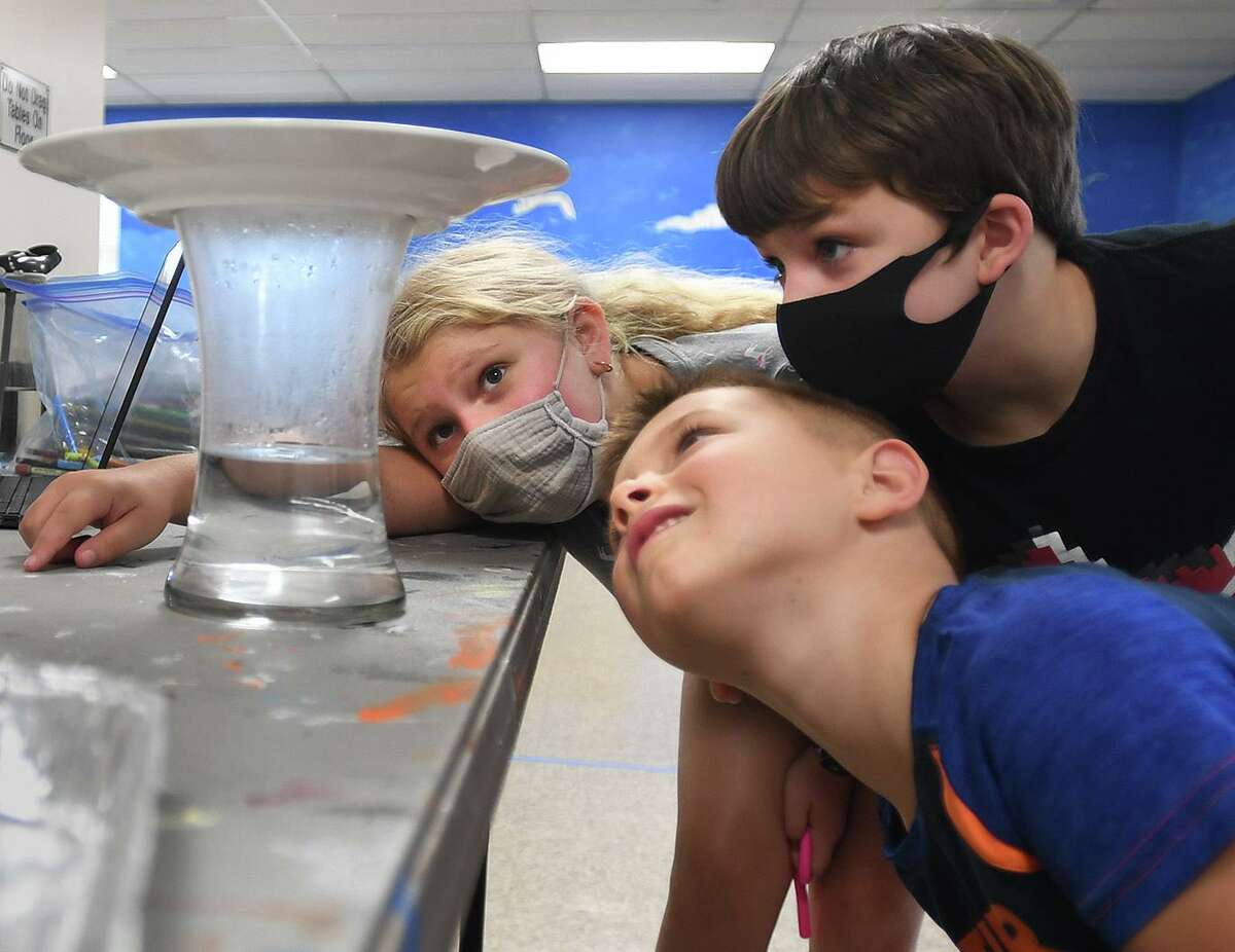 From left; Remi Brenner, 9, Michael Pietrini, 6, and Ian Bear, 9, check out the rain cloud they created during the Milford Recreation Department's one week summer meteorology camp at the Tri Beach Center in Milford, Conn. on Tuesday, July 27, 2021.