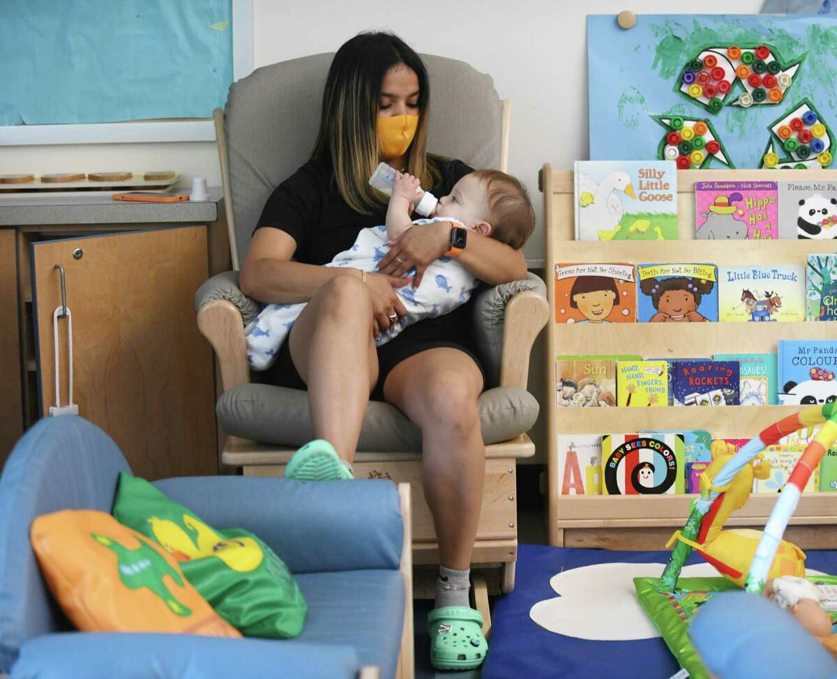 Elizabeth De Leon cares for a child at Temple Sholom's Selma Maisel Nursery School in Greenwich, Conn. Wednesday, July 28, 2021. Even before COVID-19 hit, quality day care centers were in high demand. Now, with parents returning to work, it has been difficult for many to find childcare openings in the area.