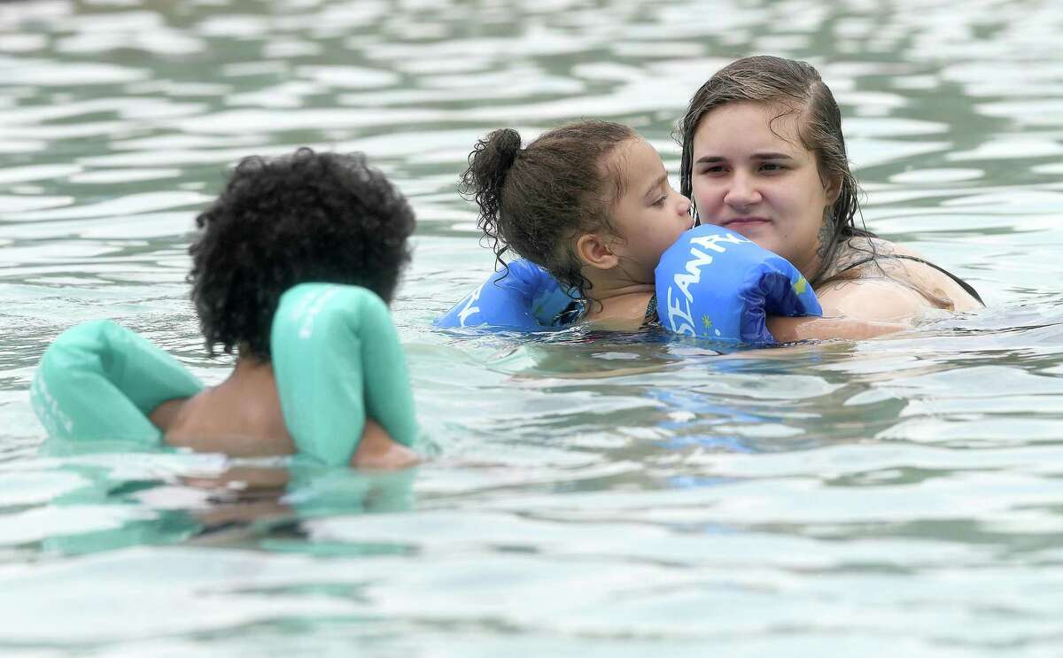 Savannah Willis holds onto daughter RiRi Garner as soon Trae Willis swims nearby while cooling off at the Alice Keith Park pool Tuesday, which was the first day of the hottest weeks of summer, according to Space City Weather. Photo made Tuesday, July 27, 2021 Kim Brent/The Enterprise