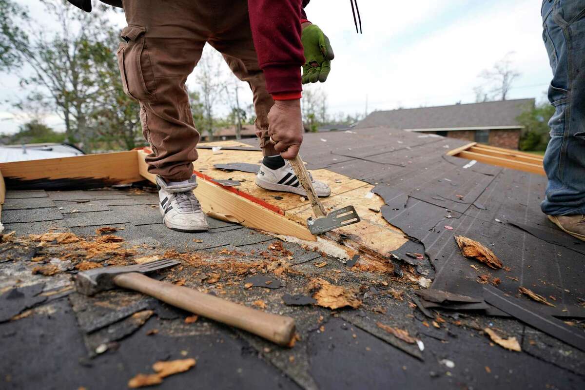 Roofers work on the heavily damaged and gutted home of Christi and Brandy Monticello, in the aftermath of Hurricane Laura and Hurricane Delta, in Lake Charles, La., Friday, Dec. 4, 2020. (AP Photo/Gerald Herbert)