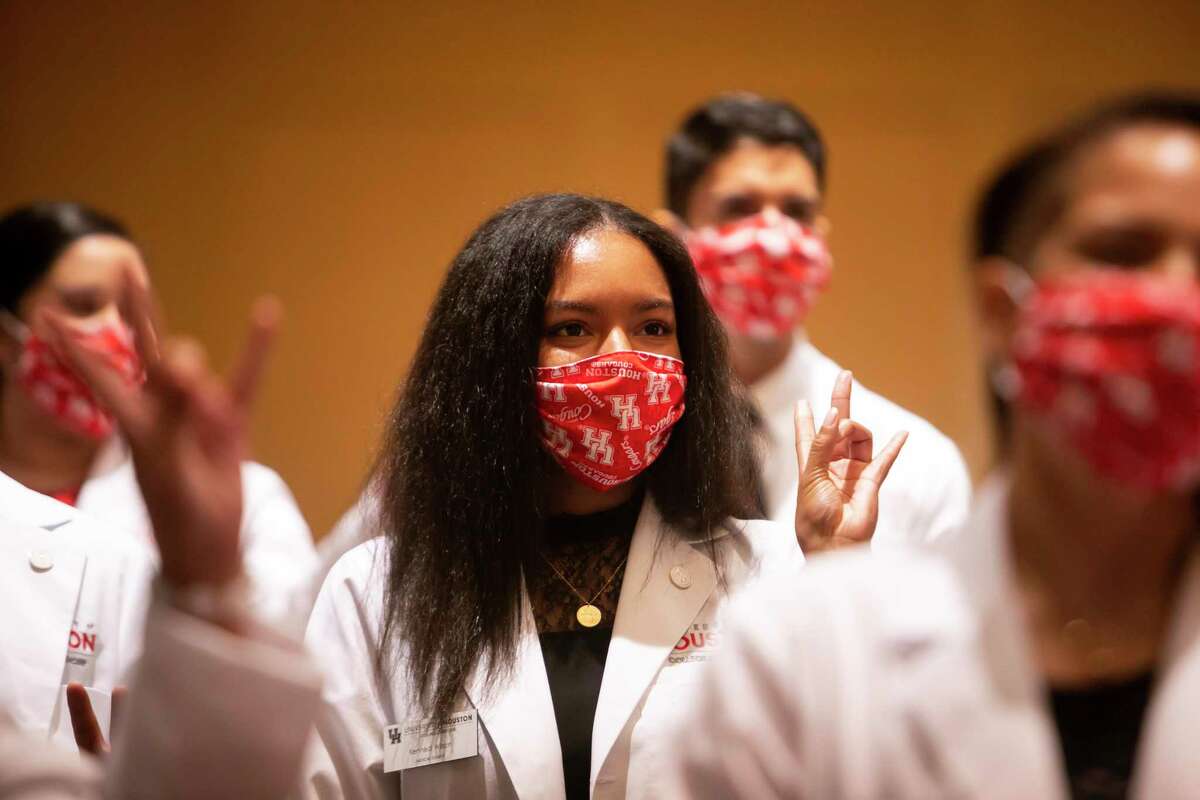 Kennedi Wilson gives the cougar hand sign during the University of Houston College of Medicine Inaugural Class White Coat Ceremony on Saturday, Aug. 8, 2020. The university welcomed and recognized 30 students as the first medical class in 50 years in Houston with an emphasis on improving public health through primary care. The students recited their class oath and received their coat.