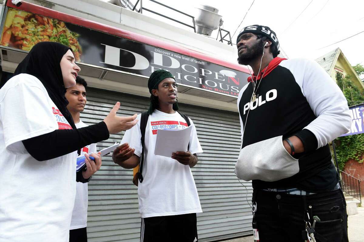 From left, Public Health College Corps members Nour Al Zouabi, Shiv Patel and Tyler Jenkins speaks with Kosh B Koolin, who is reluctant to get a COVID-19 vaccination, on Dixwell Avenue in New Haven on July 29, 2021. The Public Health College Corps is a collaboration between Quinnipiac University and the Connecticut Department of Public Health to train college students to address vaccine hesitancy and bring that information to communities with low vaccination rates in the state.