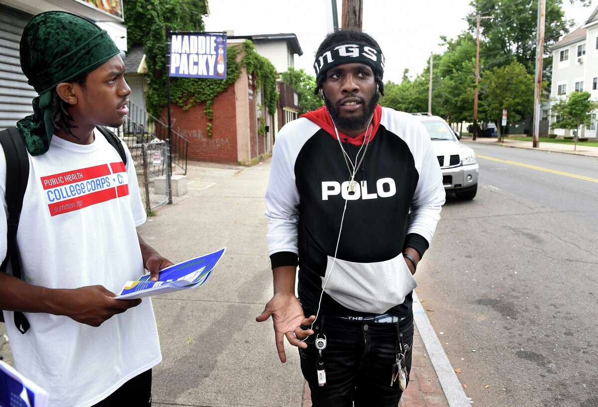 Tyler Jenkins (left) of the Public Health College Corps speaks with Kosh B Koolin, who is reluctant to get a COVID-19 vaccination, on Dixwell Avenue in New Haven on July 29, 2021. The Public Health College Corps is a collaboration between Quinnipiac University and the Connecticut Department of Public Health to train college students to address vaccine hesitancy and bring that information to communities with low vaccination rates in the state.