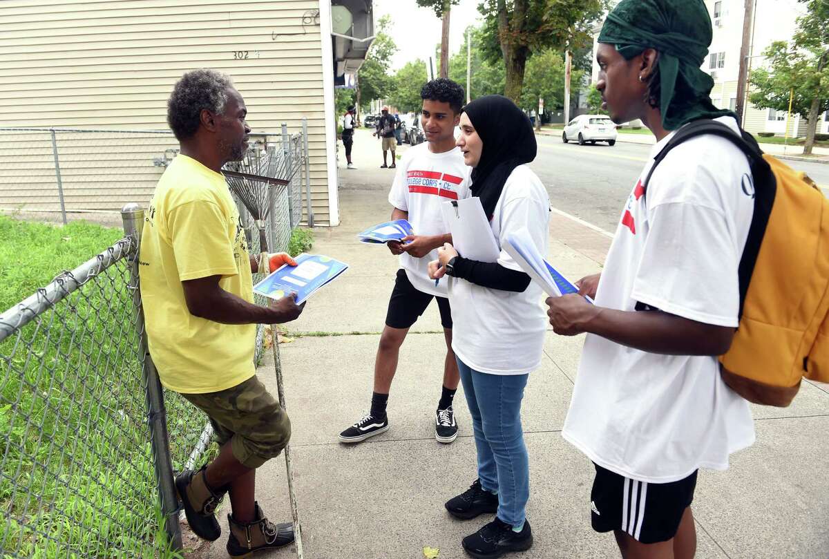 From left, Roger X of New Haven listens to Public Health College Corps members Shiv Patel, Nour Al Zouabi and Tyler Jenkins on Dixwell Avenue in New Haven on July 29, 2021 about passing along information concerning COVID-19 vaccinations to friends and family. The Public Health College Corps is a collaboration between Quinnipiac University and the Connecticut Department of Public Health to train college students to address vaccine hesitancy and bring that information to communities with low vaccination rates in the state.