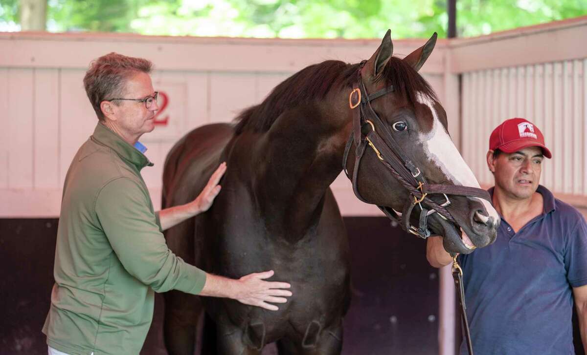 Trainer Al Stall, left, gives a friendly pat on the chest to Masqueparade while he is schooling in the paddock on Wednesday, July 28, 2021, in Saratoga Springs. The horse will make his next start in the Jim Dandy on Saturday at Saratoga Race Course.