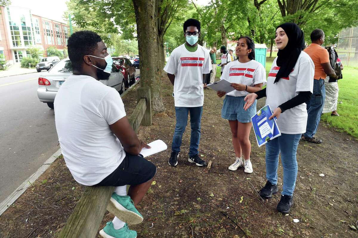 From left, Aaron Moody of New Haven listens to Public Health College Corps members Taylor Munroe Kripa Patel and Nour Al Zouabi at De Gale Field in New Haven on July 29, 2021, about passing along literature concerning COVID-19 vaccinations to friends and family.