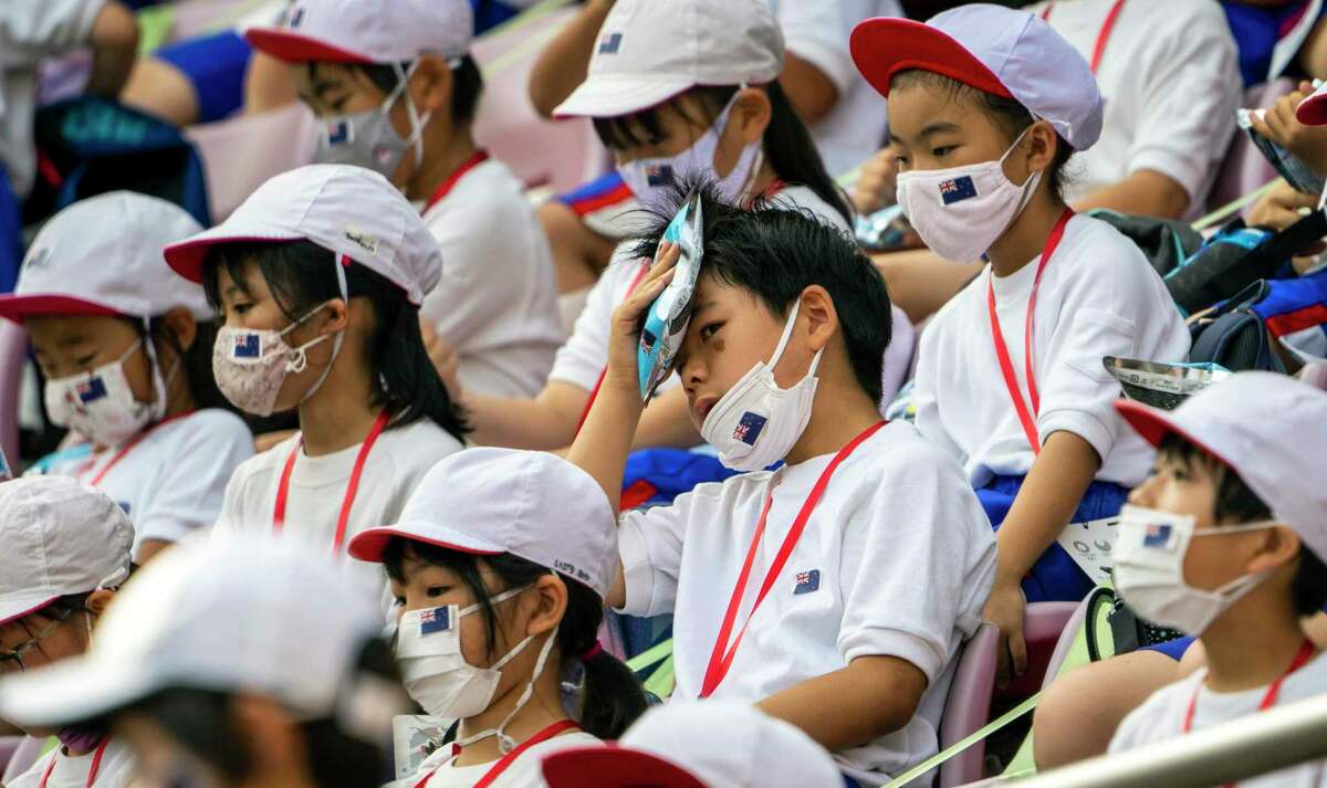 A boy holds an ice pack to his head to cool off while watching an Olympics soccer game at the Kashima Stadium in Ibaraki Prefecture, Japan, on Thursday, July 22, 2021. While fans have been barred from the majority of venues to contain coronavirus infections, three host prefectures are still allowing a limited number of spectators, mostly schoolchildren, at Olympic venues. (Doug Mills/The New York Times)