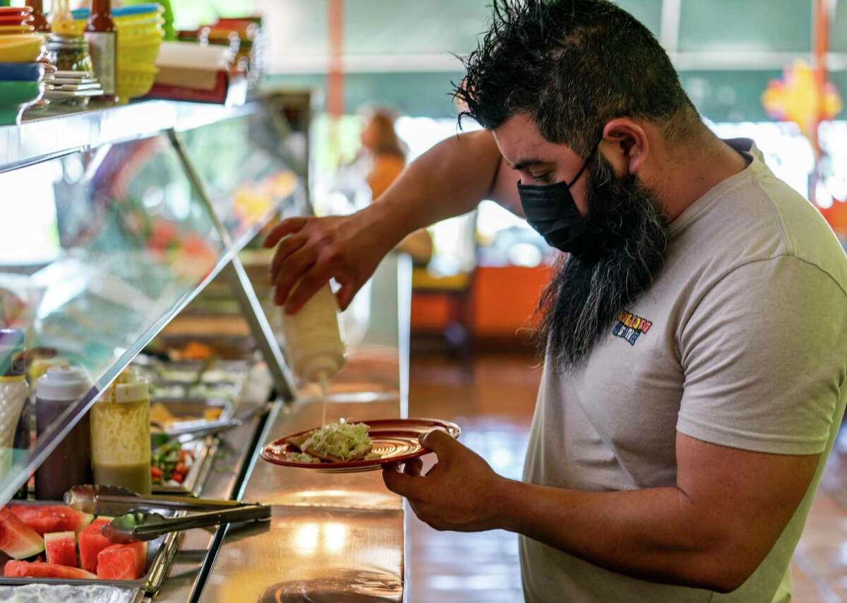 Gustavo Arellano, 36, who is vaccinated, wears a face mask as he fixes himself a plate at Taqueria El Sol buffet in Los Angeles. Masks are required for everyone indoors in Los Angeles County, and parts of the Bay Area are considering whether to follow suit.