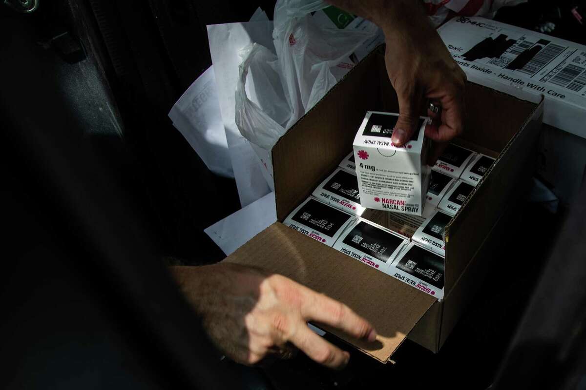 Houston Harm Reduction Alliance vice president Casey Malish picks up a box of Narcan nasal spray to deliver along with unused syringes.