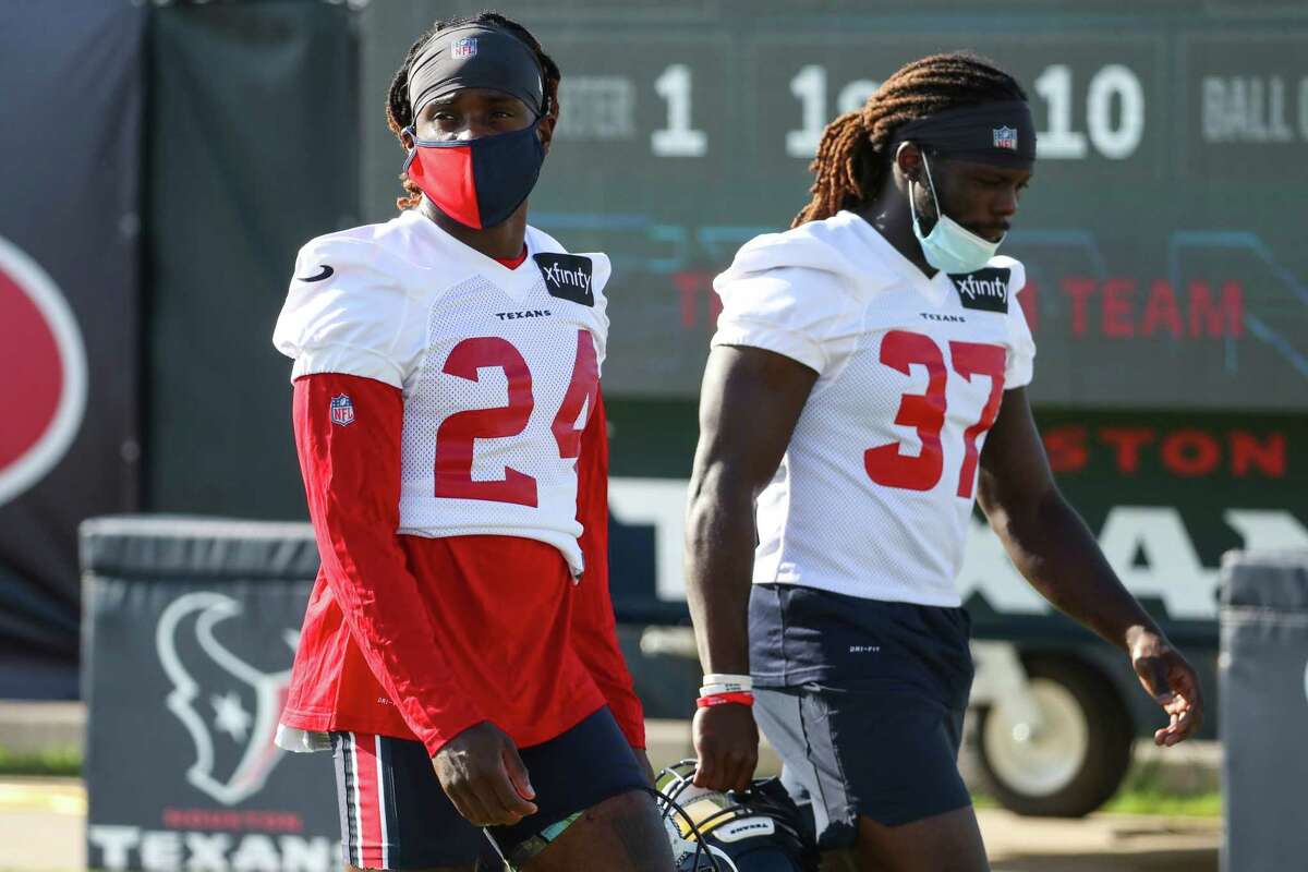 Houston Texans defensive backs Tremon Smith (24) and Tavierre Thomas (37) walk onto the field masked up during an NFL training camp football practice Friday, July 30, 2021, in Houston.