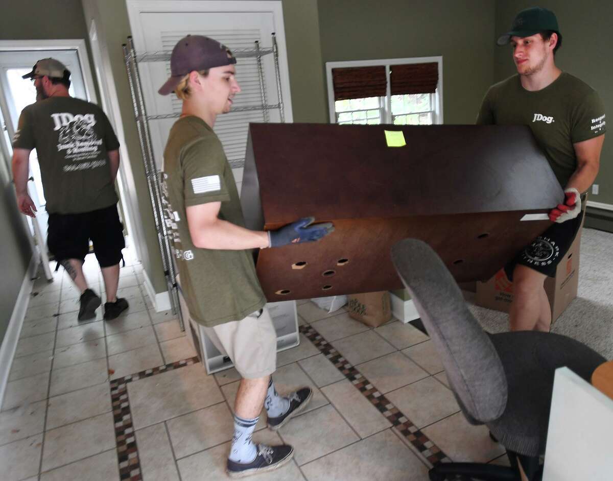From left; JDog crew members Brian Sargent, James Carcano, and Jack Price clear out a home in preparation for sale in Milford, Conn. on Thursday, July 29, 2021.