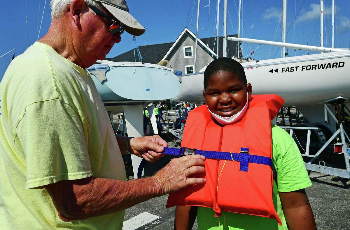 Wes Oliver helps Campers from ROSCCO (Rogers School Community Center Organization) summer vacation program including Nojah Dior Dixon, 9, get ready for a day on the water during the Noroton Yacht Club's 25th annual Boat/Camp Friday July 30, 2021, at the Yacht Club in Darien, Conn. Person-to-Person, Darien Boat Club, Darien Police Marine Unit, Noroton Fire Department, Norwalk Seaport Association, United States Coast Guard Auxiliary--Norwalk Flotilla 72 and Darien Sail and Power Squadron partner to provide a safe on-the-water experience for underserved children.
