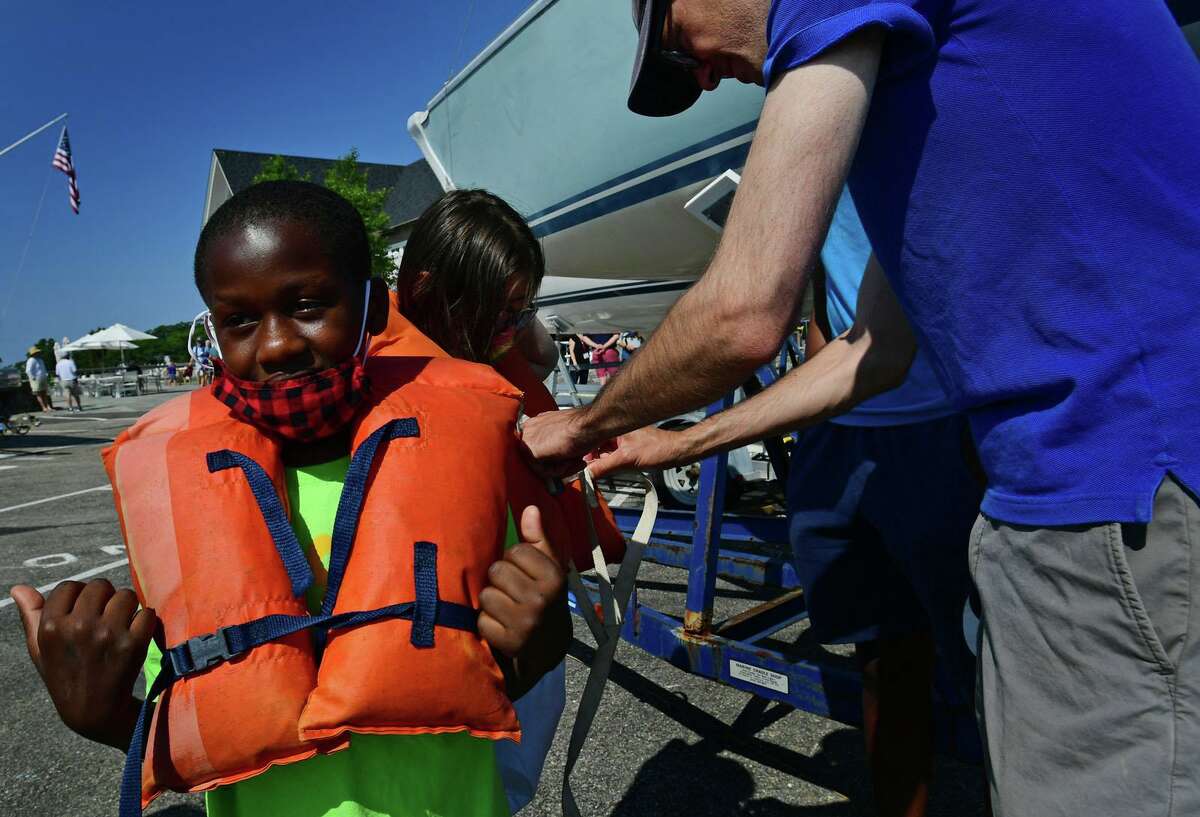 Campers from ROSCCO (Rogers School Community Center Organization) summer vacation program including Kaden Richaredson, 10, get ready to enjoy a day on the water during the Noroton Yacht Club's 25th annual Boat/Camp Friday July 30, 2021, at the Yacht Club in Darien, Conn. Person-to-Person, Darien Boat Club, Darien Police Marine Unit, Noroton Fire Department, Norwalk Seaport Association, United States Coast Guard Auxiliary--Norwalk Flotilla 72 and Darien Sail and Power Squadron partner to provide a safe on-the-water experience for underserved children.