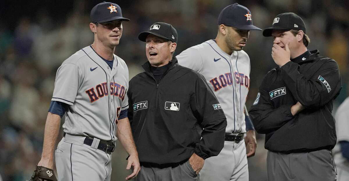 Houston Astros relief pitcher Brooks Raley, left, talks with umpire Tripp Gibson, second from left, after Raley was ejected from a baseball game against the Seattle Mariners after he hit Seattle Mariners' J.P. Crawford with a pitch during the eighth inning, Monday, July 26, 2021, in Seattle. The Mariners won 11-8. (AP Photo/Ted S. Warren)