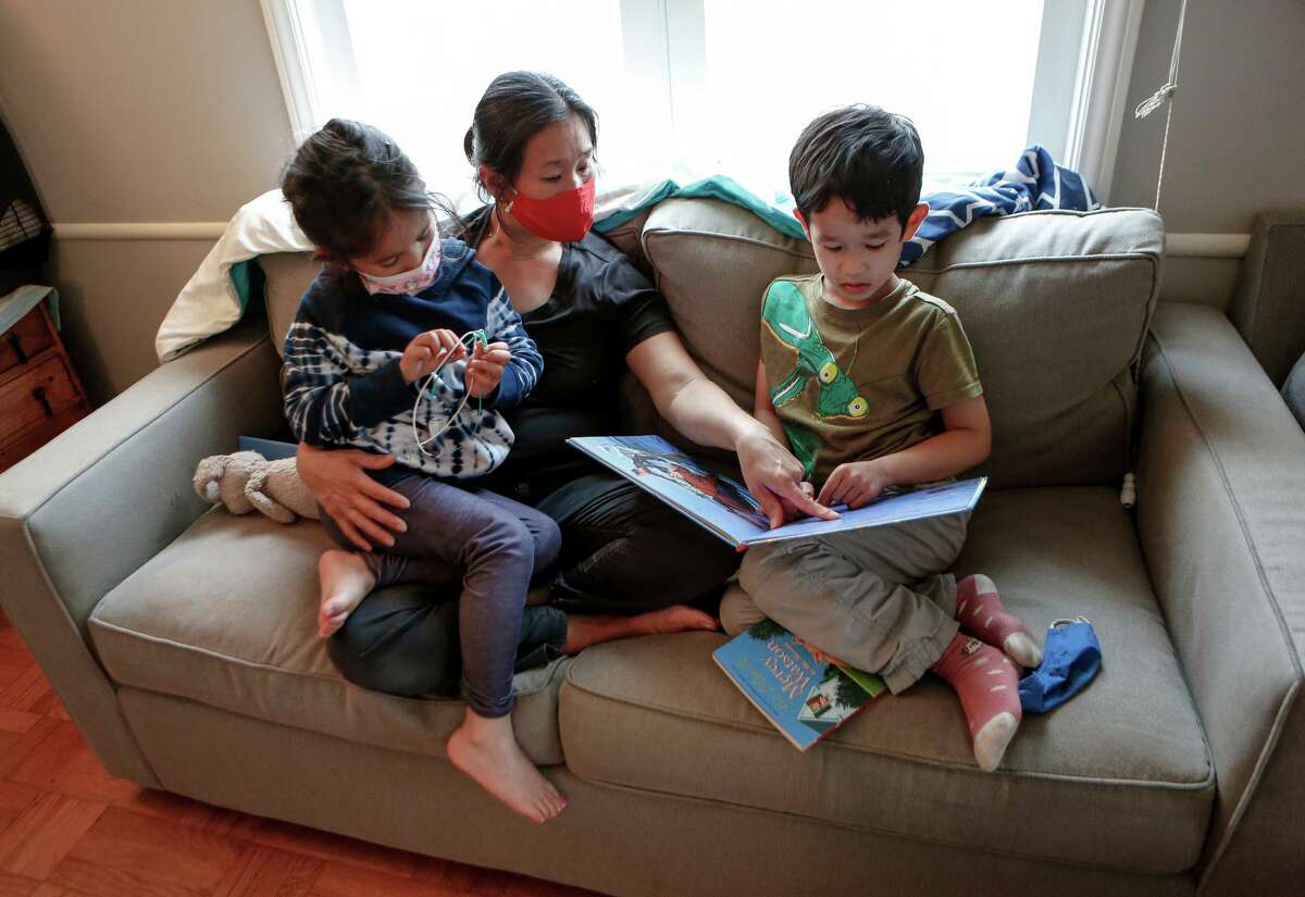 Kimberly Shu reads with her 7-year-old twins, Zoe (left) and Lucas, in their San Francisco home. Shu is a low-income single mom and doesn’t know what her children will do until she’s off work at the end of the day.