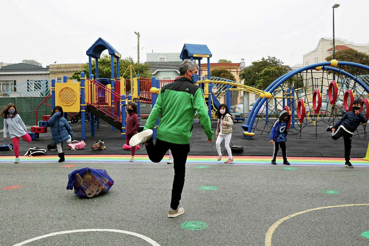 Third-grade teacher Jacob Strohm leads an exercise in the schoolyard on the first day Argonne Elementary in San Francisco is back in class.