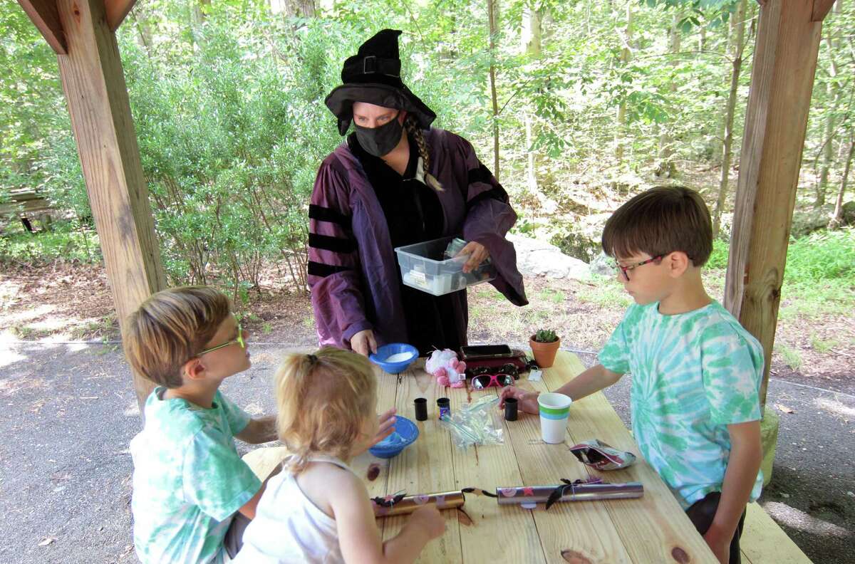 Professor Quickwit, played by Stamford Museum & Nature Center Director of Education Lisa Monachelli, hands out supplies during a potions class as part of a Wizard Picnic to celebrate Harry Potter's birthday on the grounds in Stamford, Conn., on Saturday July 31, 2021. Kids came dressed as wizards and took part in several activities like making their own wands, a potions class, a visit with some magical creatures from the nature center and snacks.