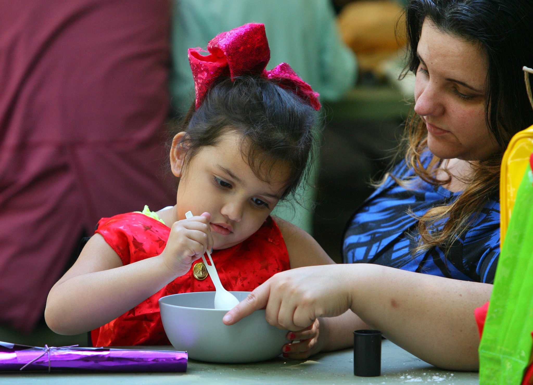 Samantha Ponce, 3, stirs ingredients in potion class as her mom Stefanie helps her hold the bowl during a a Wizard Picnic held to celebrate Harry Potter's birthday at Stamford Museum & Nature Center in Stamford, Conn., on Saturday July 31, 2021. Kids came dressed as wizards and took part in several activities like making their own wands, a potions class, a visit with some magical creatures from the nature center and snacks.