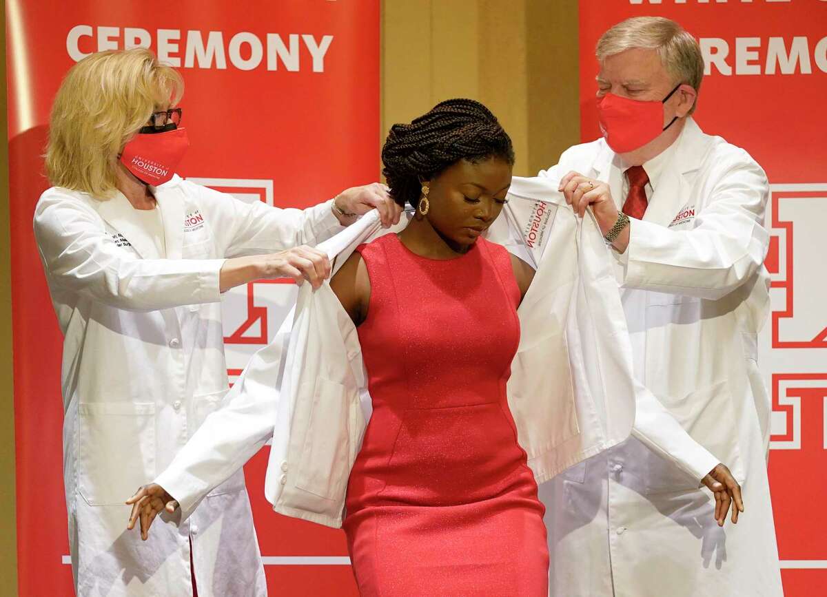 Dr. Ruth Bush, left, and Dr. Stephen Spann, put a white coat onto medical student Adebosola Karunwi, center, during the University of Houston College of Medicine ceremony held at the Hilton UH Saturday, July 31, 2021 in Houston.
