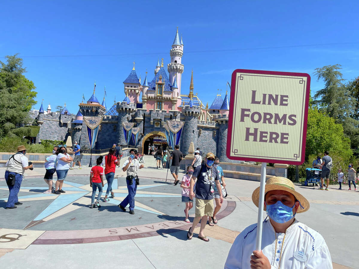 A Disneyland employee forms a line for visitors to take pictures in front of Sleeping Beauty Castle in Anaheim, CA, on Friday, April 30, 2021.