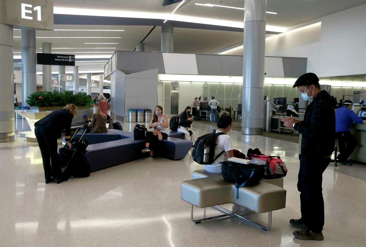 Travelers organize carry-on items after security screening at SFO in 2020. As the airline industry sees a modest rise in travel, a rapid COVID-19 testing site has been set up at the airport to provide travelers with documentation of test results to present upon arrival at their final destinations.