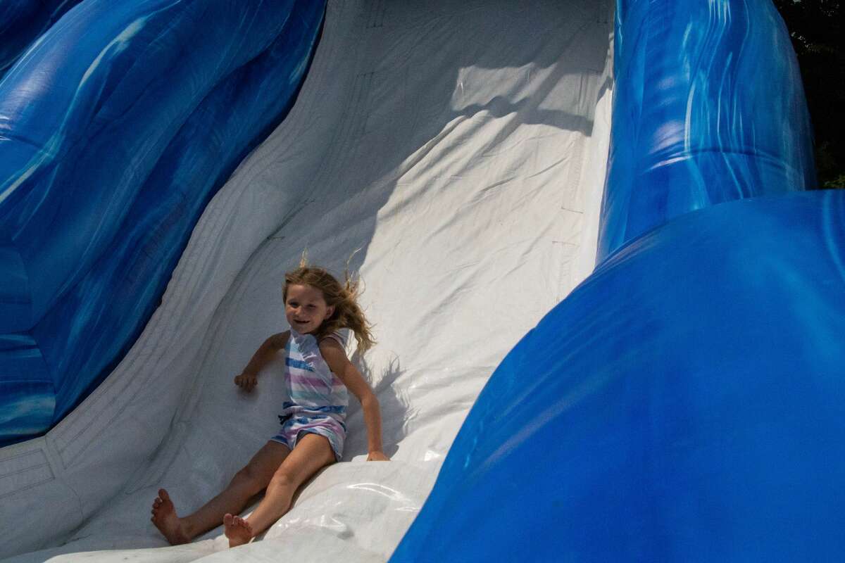 Taliesyn, 7, goes down an inflatable slide on her birthday at Pop Up Palooza Sunday, Aug. 1, 2021 in Sanford's Porte Park. (Drew Travis/for the Daily News)
