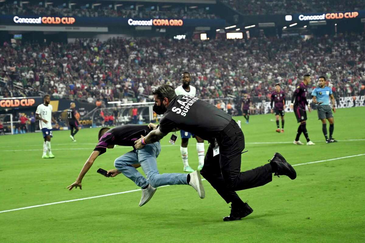 A security guard tackles a spectator who ran on the field during the second half of the CONCACAF Gold Cup final soccer match between United States and Mexico Sunday, Aug. 1, 2021, in Las Vegas. (AP Photo/David Becker)