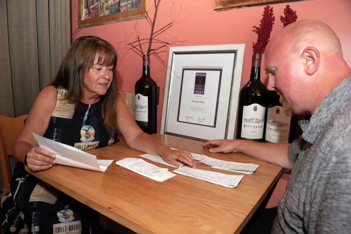 Owner Patty Novo goes over tips on receipts with server Paul Woodcock at Taverna Novo in Saratoga Springs. (Lori Van Buren/Times Union)