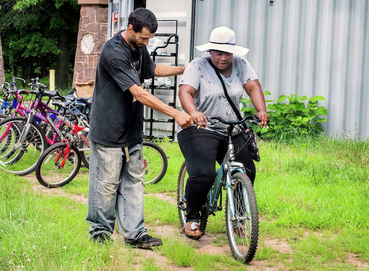 Alex Martinez, left, helps Salamatu Mohammed get started riding one of the bicycles provided for use by the Learning Corridor. Martinez is a Newhallville resident and works for the Community Placement Engagement Network.