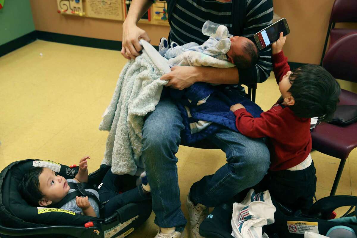 Eric Mora feeds his newborn son, Noah, as he sits with his other sons, Niovani, 1, left, and Eric Mora, Jr., 2, at the South Flores Women, Infant and Children Clinic, Wednesday, November 28, 2018. His wife, Adriana Rodriguez, was enrolling Noah, who was born on November 22nd in the program. Mora, a tile setter, said work is not consistent making it difficult for the family. According to a new report, one in five uninsured American children lives in Texas, the state with the highest number of children who lack coverage for basic health needs.