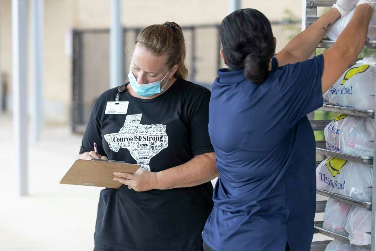 Shanna Trevino, left, logs in the amount of meals distributed during a food distribution event at Oak Ridge High School in Conroe in 2020. As part of the response to COVID-19, school districts in Montgomery County began to offer free breakfast and lunch to all students last school year. This year, the free meals will continue.