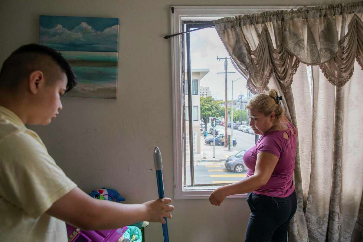 From left: Alan Lopez, 13, helps her mother Victoria Medina clean their San Francisco apartment. Medina is hoping state or local rent relief programs will help her family stay in their longtime home.